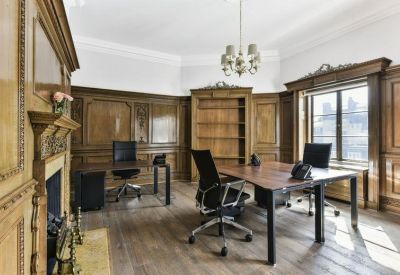 Private office suite with wood-paneled walls, a fireplace, and two modern workstations.