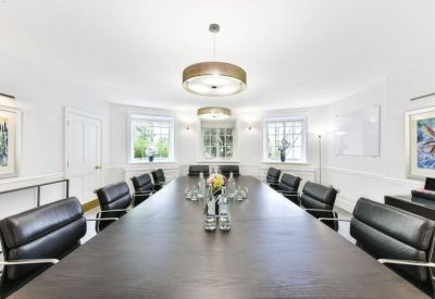 Symmetrical boardroom with a long dark wood table, leather chairs, and two circular pendant lights.
