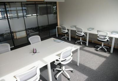 Minimalist office space with white desks and mesh ergonomic chairs.