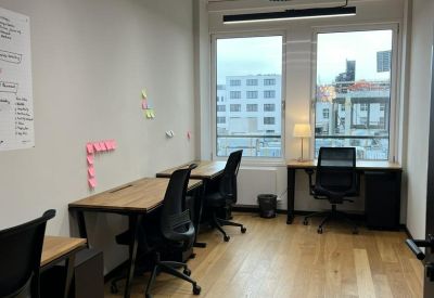 Private office at 32 Uhlandstraße with wooden desks, ergonomic chairs, and large windows with city views.