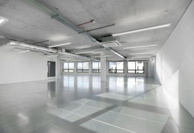 Bright, open-plan office space with polished concrete floors and minimalist white walls.