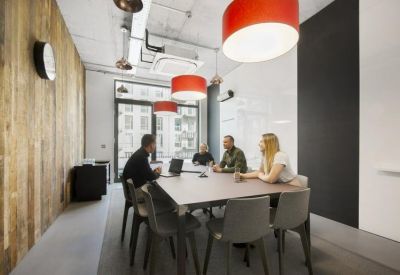 Modern meeting room featuring a wooden accent wall and red drum pendant lights.