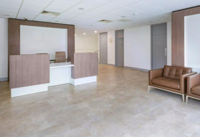Bright, modern reception area with wooden desk and leather armchairs.