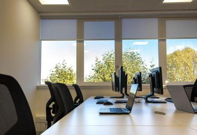 Bright open-plan workspace with multiple desk stations and large windows.