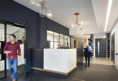 Modern reception area with a marble desk, dark feature wall, and decorative globe lighting.