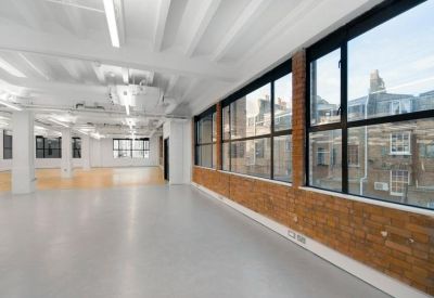 Bright open-plan workspace with exposed brick walls and white beamed ceilings.