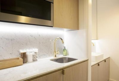 Sleek kitchenette with marble backsplash and a gold faucet.