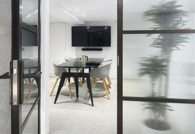 View into a modern meeting room through glass doors with a frosted plant design.
