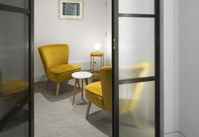 Quiet breakout space with two vibrant yellow velvet armchairs and a small side table.
