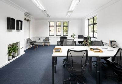 Open plan office suite with white desks, mesh chairs, and large windows.