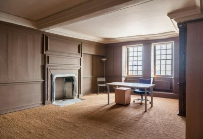 Private office with a stone fireplace and twin windows overlooking the street.