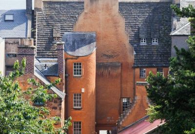 Detailed exterior view of the tall orange-hued stone facade and multi-level roofline.