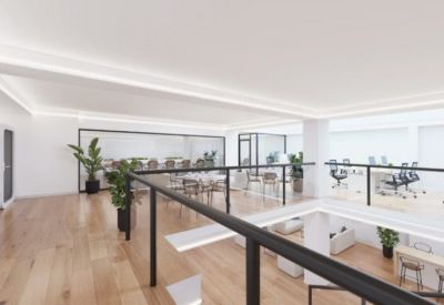 Upper level mezzanine overlooking the lounge area with glass railings and office desks.