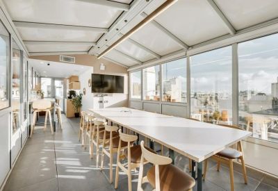Enclosed glass conference room with a long white table and panoramic city views.