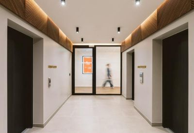 Minimalist elevator lobby with white walls, dark wood accents, and recessed lighting.