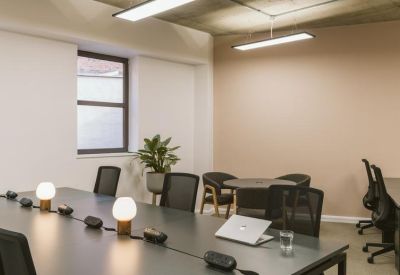 Bright workspace with a long conference table, ergonomic chairs, and large windows.