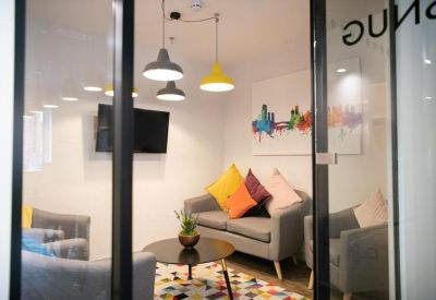 Modern lounge area with grey sofas, colorful pillows, and contemporary pendant lighting.