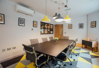Sleek meeting room featuring a dark wood table, black leather chairs, and a geometric yellow rug.