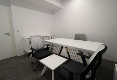 Bright private office featuring a white desk, grey mesh chairs, and a white storage cabinet.