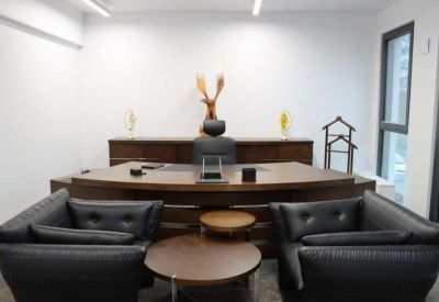 Office suite with a curved wood executive desk and black leather seating.