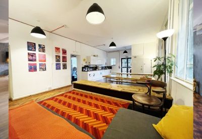 Vibrant breakout lounge with a geometric orange rug and kitchen area in the background.