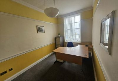 Spacious office suite with warm yellow walls and a large L-shaped wooden desk.