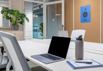 Bright office suite with white desks, ergonomic chairs, and a laptop.