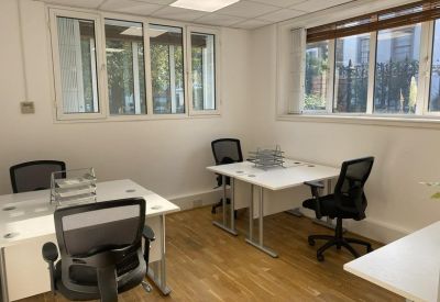 Four-person office space with two desks and natural light from multiple windows.