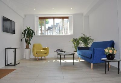 Lounge area with a blue sofa, yellow armchair and stylish coffee tables.