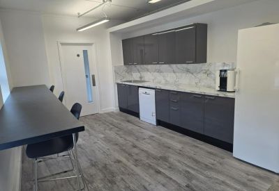 Sleek communal kitchen with grey cabinetry and a marble-effect backsplash.