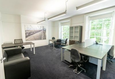 Bright open-plan office with multiple desks, large windows, and a landscape wall mural.