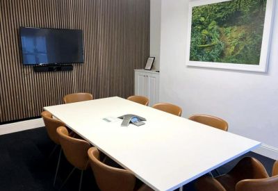 Modern meeting room with a white table, tan leather chairs, and a slatted wood feature wall.