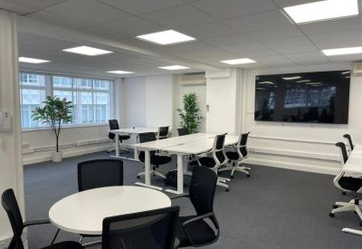 Modern meeting room featuring a white round table, black chairs, and a large digital display.