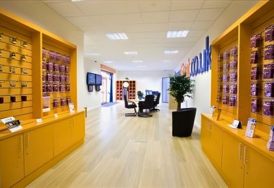 Reception area with bright yellow shelving, wooden floors, and a seating area.