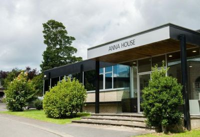 Modern building entrance with Anna House signage and green landscaping.