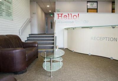 Reception area featuring a curved desk, brown leather sofa, and glass coffee table.
