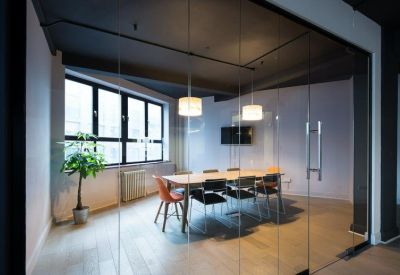 Private glass-walled meeting room with a wooden table and black chairs.
