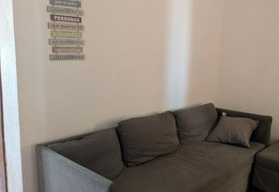 Comfortable grey sofa against a white wall decorated with a wooden hanging sign.