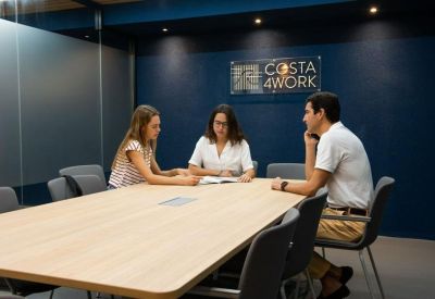 Small meeting room with three people and a Costa 4Work sign.
