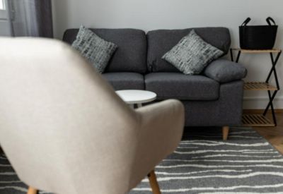 Cozy lounge area with a dark grey sofa, striped rug, and herringbone wood flooring.