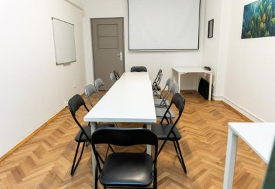 Bright conference room with a long white table, black folding chairs, and a projector screen.