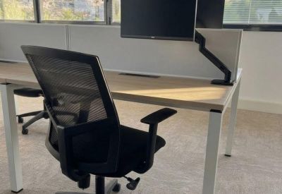 Modern workstation with an adjustable monitor arm and ergonomic mesh chair.