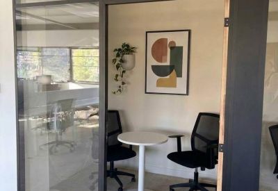 Small private meeting pod with a round white table and two black chairs.