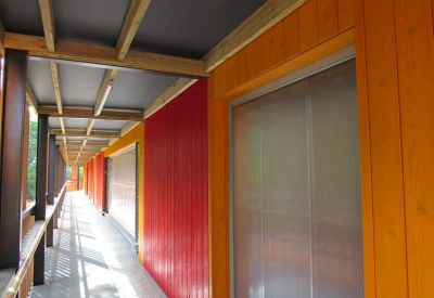 Outdoor corridor with vibrant red and yellow timber cladding and covered walkway.