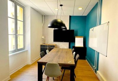 Professional meeting room with a large wooden table, wall-mounted screen, and teal accent wall.