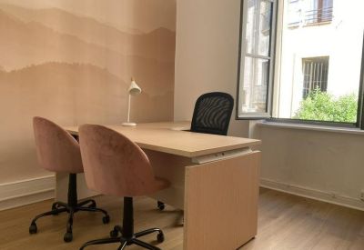 Private office suite with a wooden desk, pink velvet chairs, and soft mountain-pattern wallpaper.