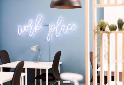 Close-up of a workstation area featuring a neon sign and modern pendant lighting.