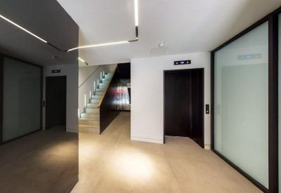 Sleek office lobby with polished floors, modern strip lighting, and elevator entrance.