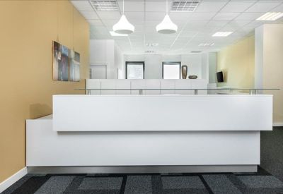 Clean white reception desk in a modern lobby with warm tan walls and hanging pendant lights.