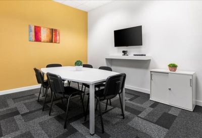 Meeting room with a white table, black chairs, a yellow feature wall, and a wall-mounted TV.
